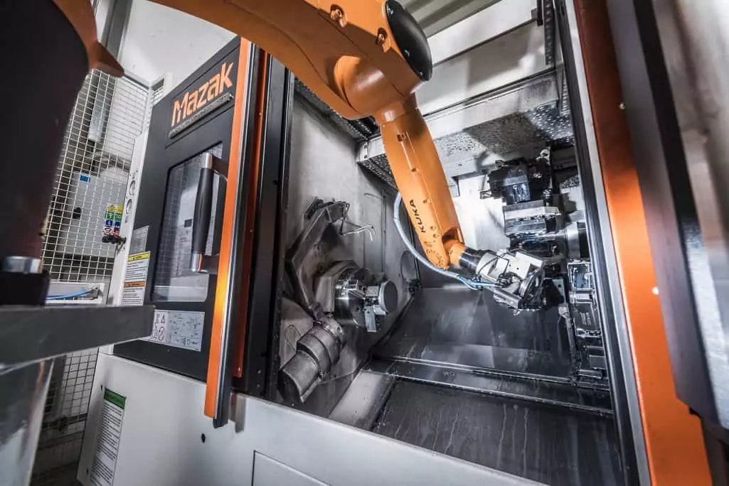 kuka robotic arm loading a mazak cnc machine with an aluminium part in factory